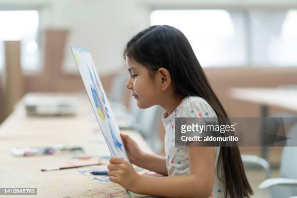 little girl looking at painting very close - myopia 個照片及圖片檔