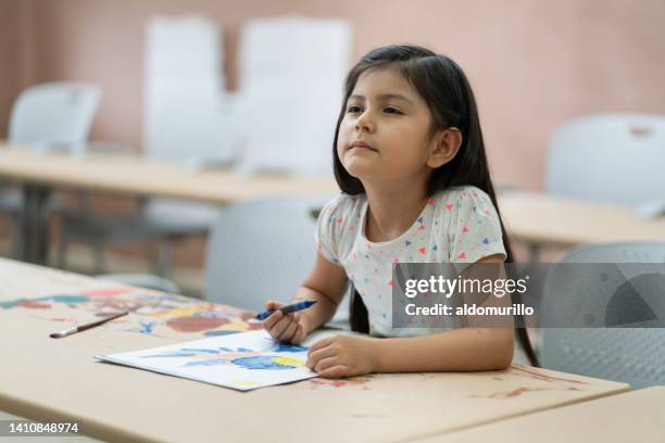 little girl sitting in class and squinting to see board - myopia 個照片及圖片檔