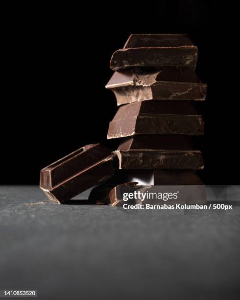 close-up of chocolates on table against black background - chocolate bar stock pictures, royalty-free photos & images