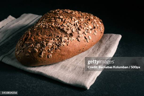 high angle view of bread on cutting board over black background - close up bread roll black backdrop horizontal stock pictures, royalty-free photos & images