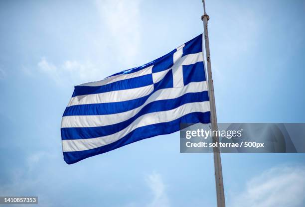 low angle view of greek flag against blue sky - eurozone debt crisis stock pictures, royalty-free photos & images