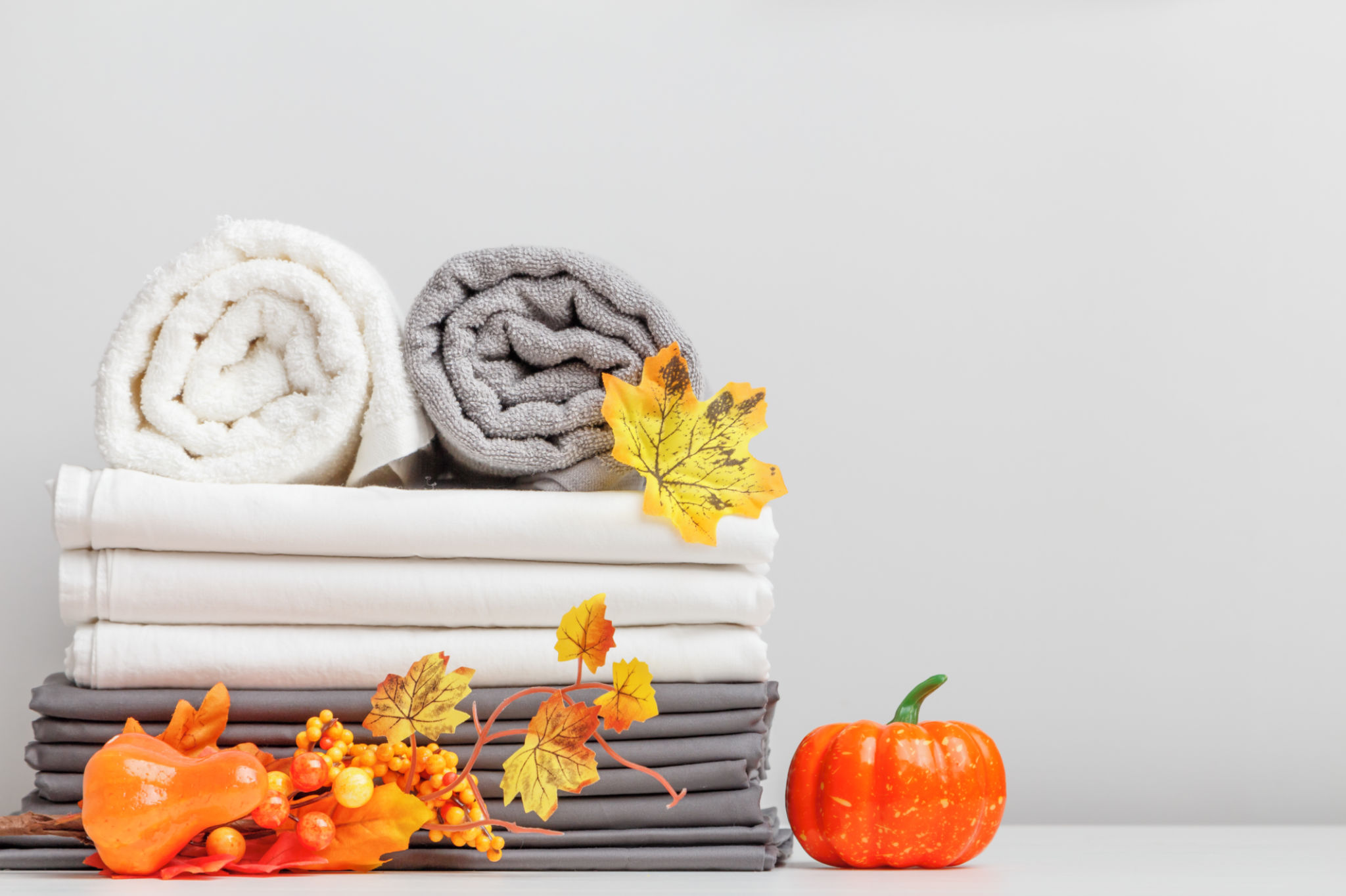 White and gray linen, bed sheet and two folded towels on a table with halloween decor. White and gray linen, bed sheet and two folded towels on a table with halloween decor.