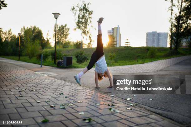 7-year-old child makes wheel on his hands with his feet up in summer on sport ground in city yard - acrobatic activity photos et images de collection