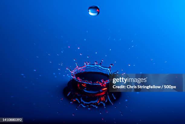 close-up of splashing droplet against blue background,tarleton,united kingdom,uk - impact stock pictures, royalty-free photos & images