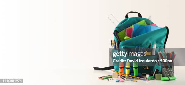 blue school backpack full of school supplies on white table - open backpack stock pictures, royalty-free photos & images