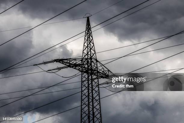 electricity pylon with dramatic clouds - blackout picture stock-fotos und bilder