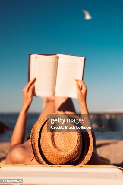 woman reads a book on the beach. - beach book reading stock pictures, royalty-free photos & images