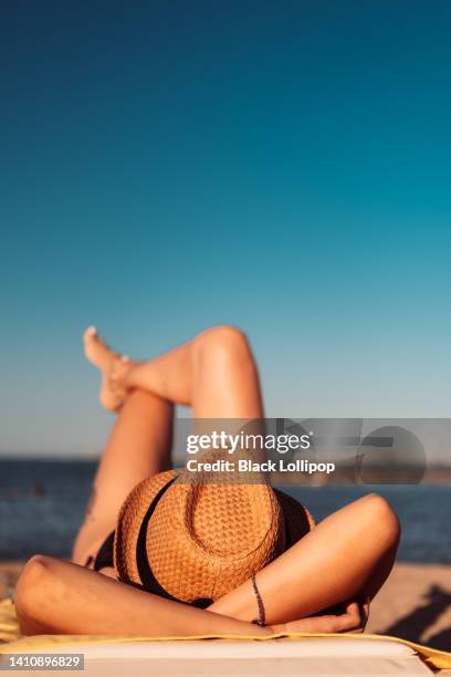 femme avec un chapeau de paille se reposant et se relaxant sur la plage. - chapeau de paille photos et images de collection