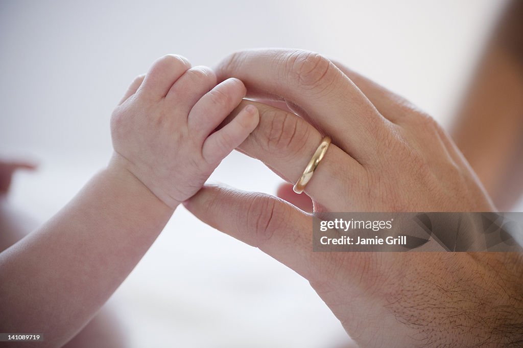 Baby holding father's finger, close-up