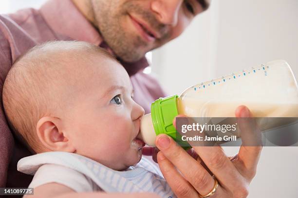 father feeding baby a bottle - saugen mund benutzen stock-fotos und bilder