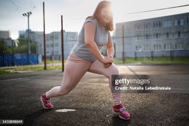 teenage girl of 12 years old with overweight in pink leggings does sports exercises - chubby girls photos fotografías e imágenes de stock