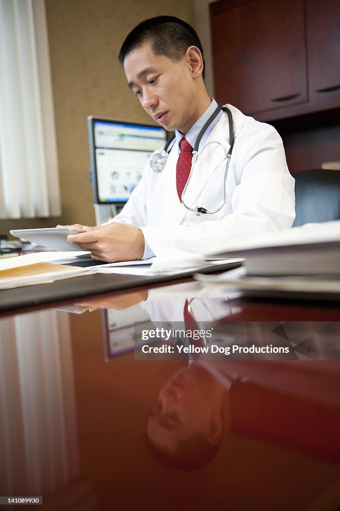 Doctor in his Office looking at Digital Tablet