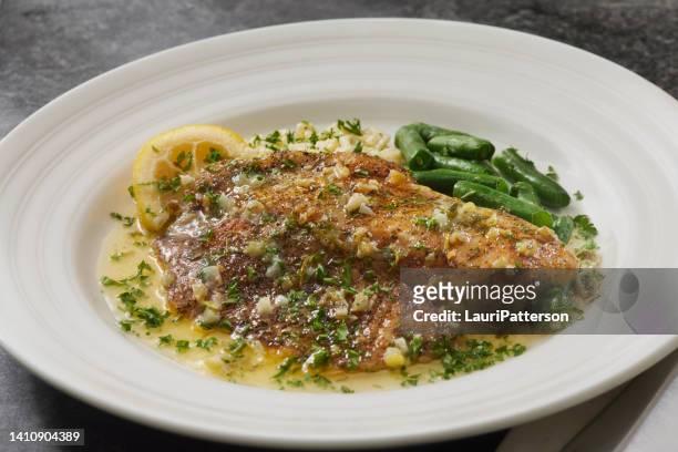 baked tilapia in a lemon, garlic and butter sauce - cod dinner stock pictures, royalty-free photos & images