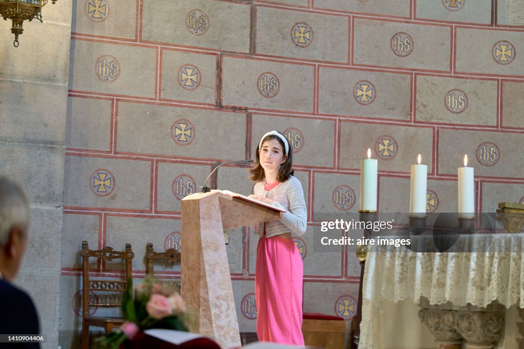 White girl 15 years old reading at the podium of the mass in the catholic church looking at the camera