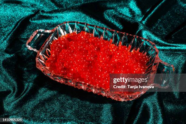 xmas modern dinner table setting. red caviar on green velvet fabric background. creative merry christmas celebration concept. contemporary new year festive backdrop - caviar stock pictures, royalty-free photos & images