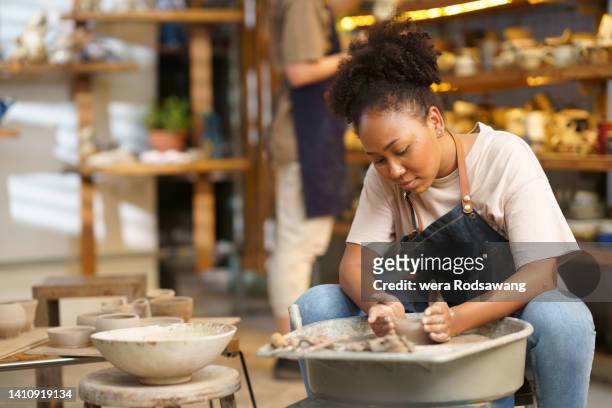 young woman molding clay on pottery wheel - craft show photos et images de collection