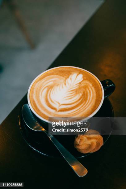 image of hot latte coffee with latte art on wooden table - coffee art stockfoto's en -beelden