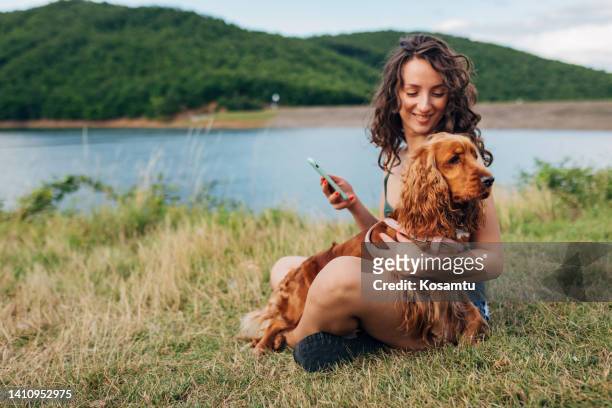 a beautiful cocker spaniel dog and its owner rest near the lake, enjoying nature - cocker spaniel 個照片及圖片檔