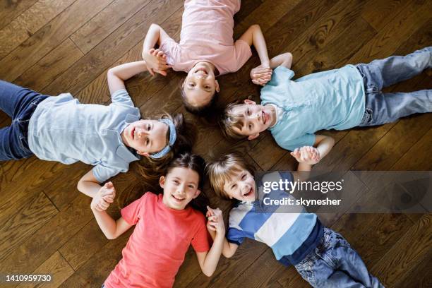 above view of happy kids holding hands on the floor. - children circle floor stock pictures, royalty-free photos & images