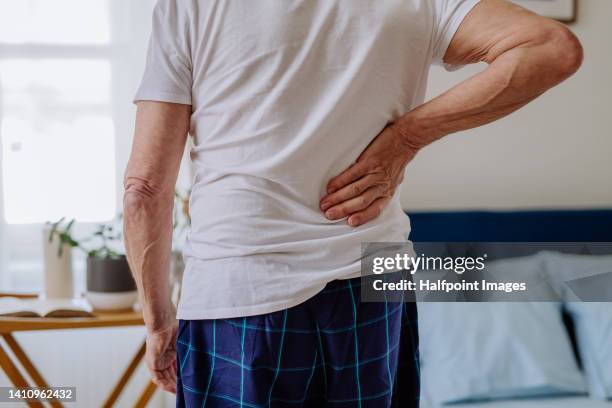 senior man having back pain, standing in his bedroom. - back pain bed stock pictures, royalty-free photos & images