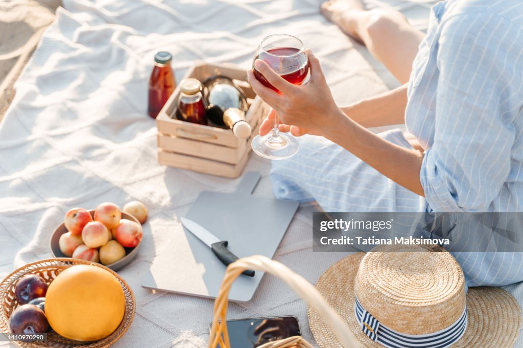 A beautiful young woman is having a good time on the beach on a picnic. A sunny summer day.