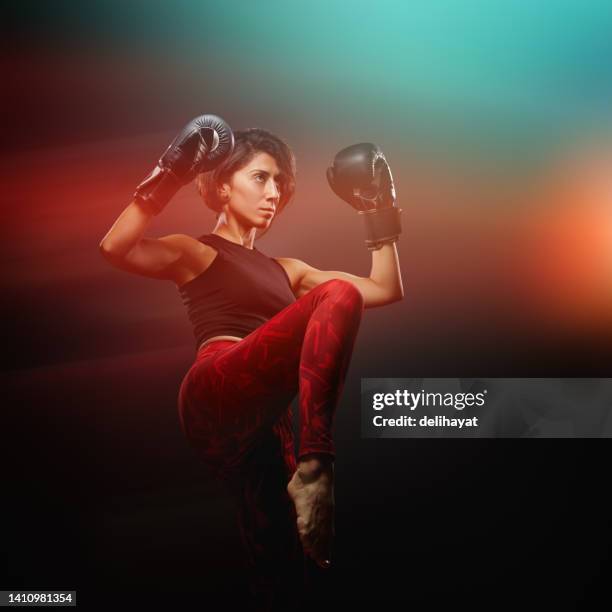 fit and muscular female fighter about to give a high kick to her contender - kickboxing gloves stock pictures, royalty-free photos & images