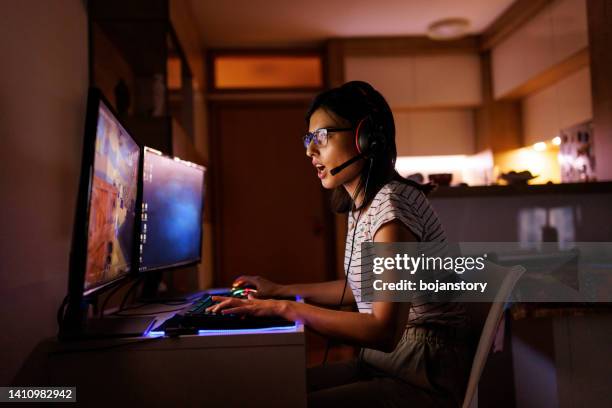 beautiful young woman playing video game on her pc at home - massively multiplayer online game stock pictures, royalty-free photos & images