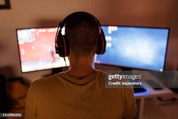 young man livestreaming while playing multiplayer online game in the evening at home - back in the game stock pictures, royalty-free photos & images