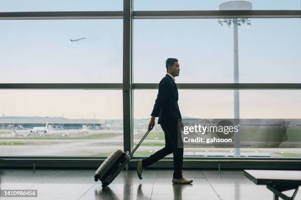 geschäftsmann mit koffer zu fuß am flughafen - anzug ausland stock-fotos und bilder