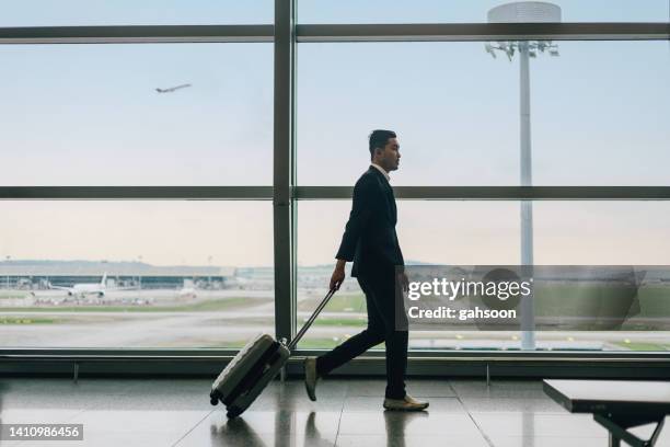 businessman with suitcase walking in airport - hong kong international airport stock pictures, royalty-free photos & images