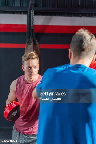 due amici del pugile maschio che si allenano con pugni e kick boxing l'uno con l'altro - sparring foto e immagini stock