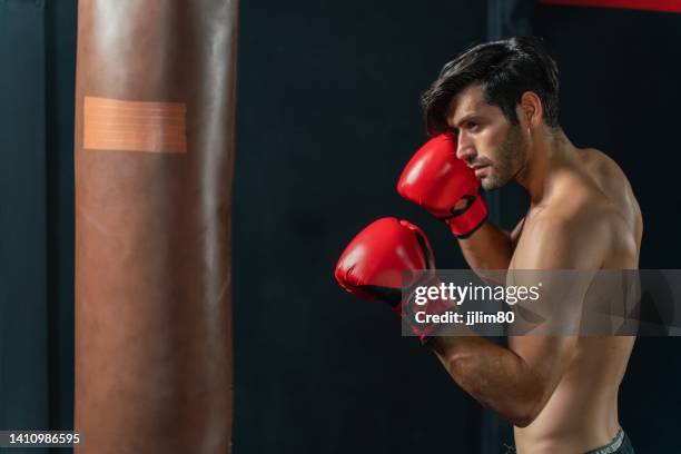 young and handsome male boxer with muscular build body with red gloves training in a gym - vechtsport stockfoto's en -beelden