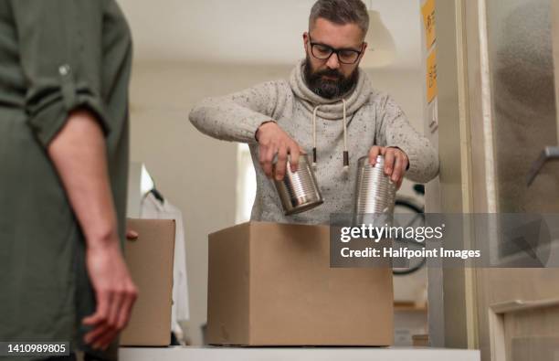 mid adult volunteer man giving cans donations for charity. - poor service delivery 個照片及圖片檔