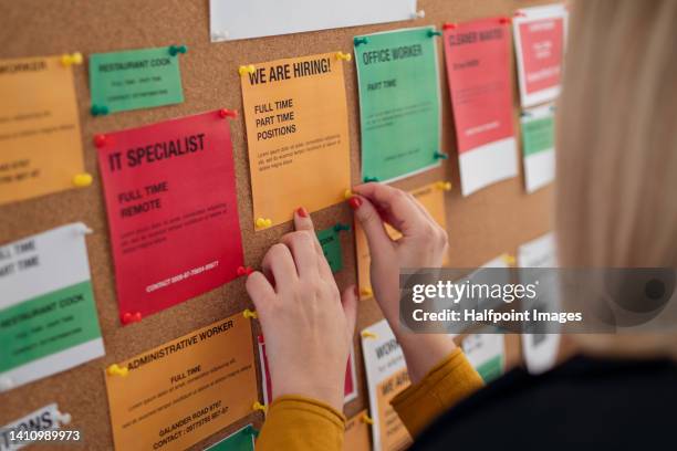 close-up of young volunteer woman pinning job vacancies on bulletin board. rear view. - placa de vaga imagens e fotografias de stock