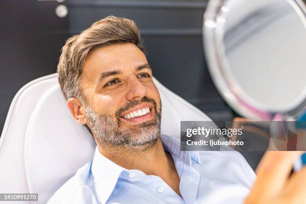 middle aged man reviewing wrinkles in hand mirror. - gezichtsbehandeling stockfoto's en -beelden