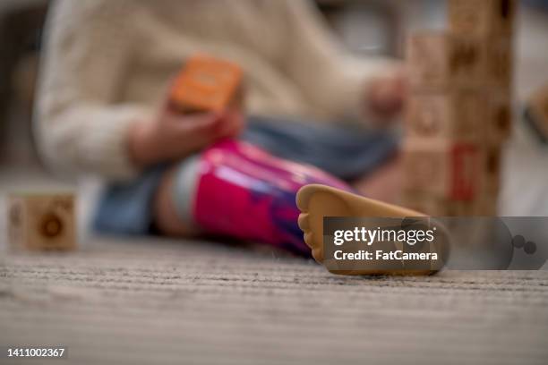 little girl with prosthetic leg playing with blocks - prosthetics stock pictures, royalty-free photos & images