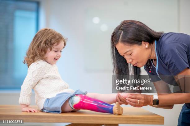 little girl with prosthetic leg at medical appointment - amputee rehab stock pictures, royalty-free photos & images