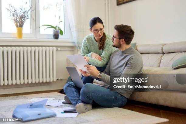 couple sitting in their living room and checking their finances using laptop - demonstration against the marriage for all bill stock pictures, royalty-free photos & images