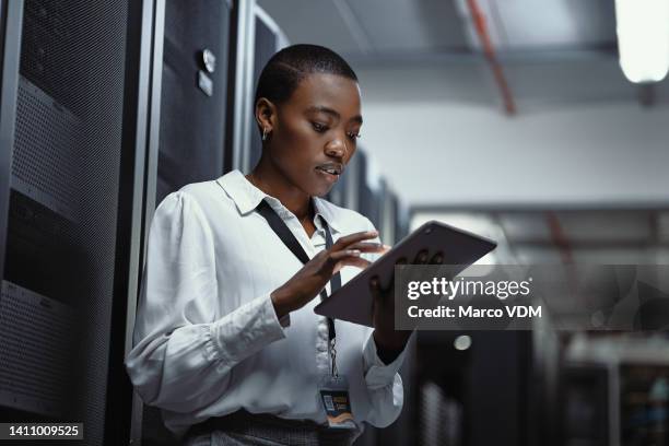 it technician using a digital tablet in a server room. female programmer fixing a computer system and network while doing maintenance in a datacenter. engineer updating security software on a machine - beveiligingssysteem stockfoto's en -beelden