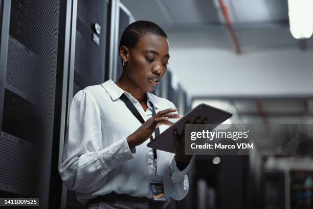 it technician using a digital tablet in a server room. female programmer fixing a computer system and network while doing maintenance in a datacenter. engineer updating security software on a machine - security system stock pictures, royalty-free photos & images