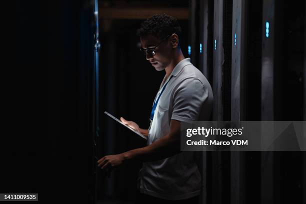 it technician with a digital tablet working in a dark server room doing hardware repairs. computer engineer working on data storage unit using wireless technology, updating software programs. - man server room stock pictures, royalty-free photos & images