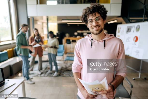 young casually clothed game designer posing in the office - adult education stock pictures, royalty-free photos & images
