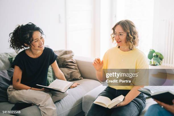 young woman discussing a lecture with book club friends - shared living room stock pictures, royalty-free photos & images