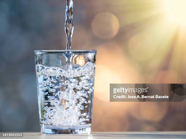 filling a glass of water to drink illuminated by sunlight. - purified water 個照片及圖片檔
