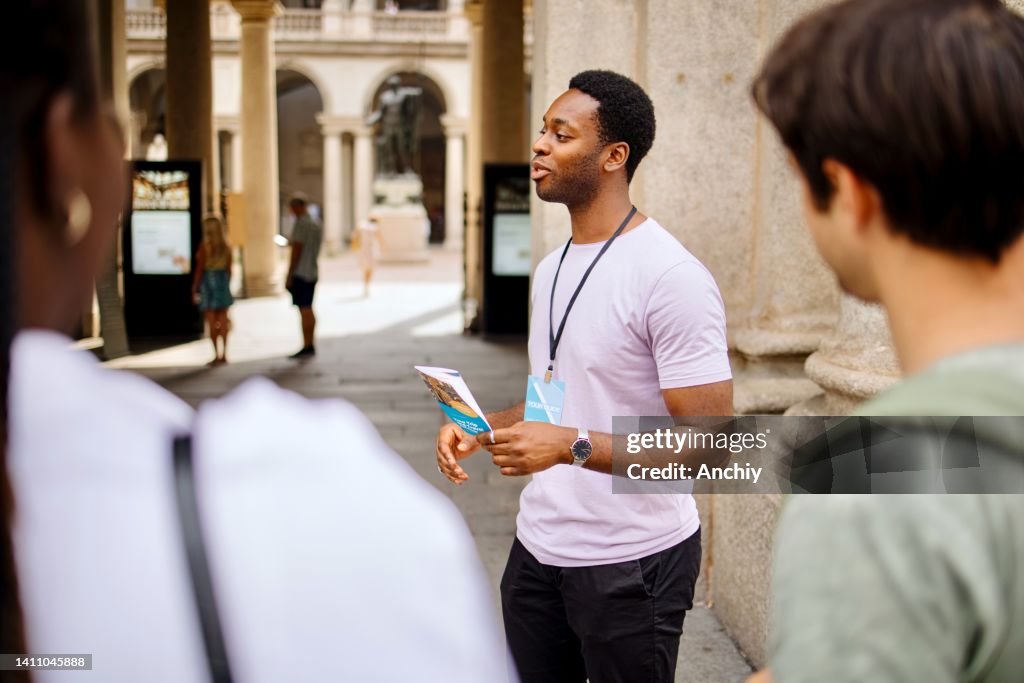 Tour guide holding guidebook and talks about famous city sights