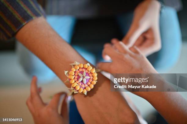 cropped hands of sister tying rakhi on brother’s hand - akhi stock pictures, royalty-free photos & images