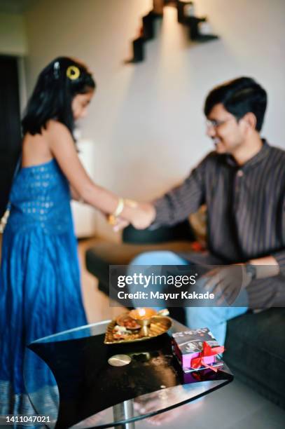 sister tying rakhi on brother's hands on rakshabandhan - raksha bandhan stock pictures, royalty-free photos & images