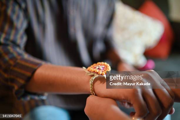 cropped hands of sister tying rakhi on brother’s hand - rakhi ストックフォトと画像