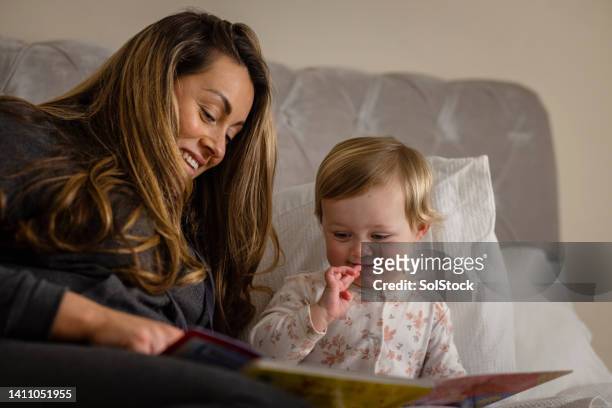 reading to her daughter - nighttime routine stock pictures, royalty-free photos & images