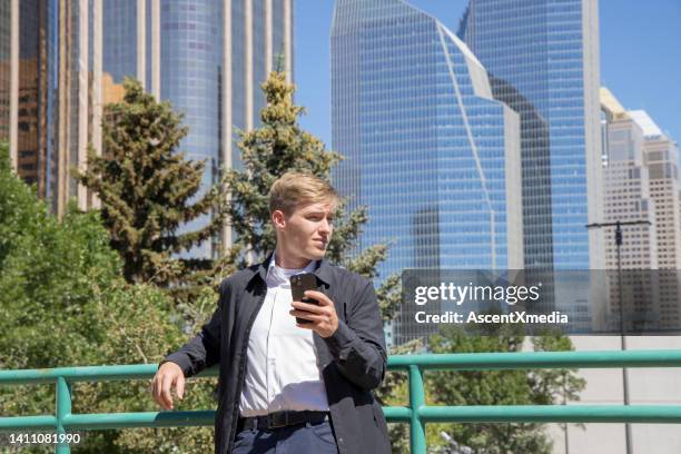 young business executive relaxes in urban environment, business district - calgary downtown stock pictures, royalty-free photos & images